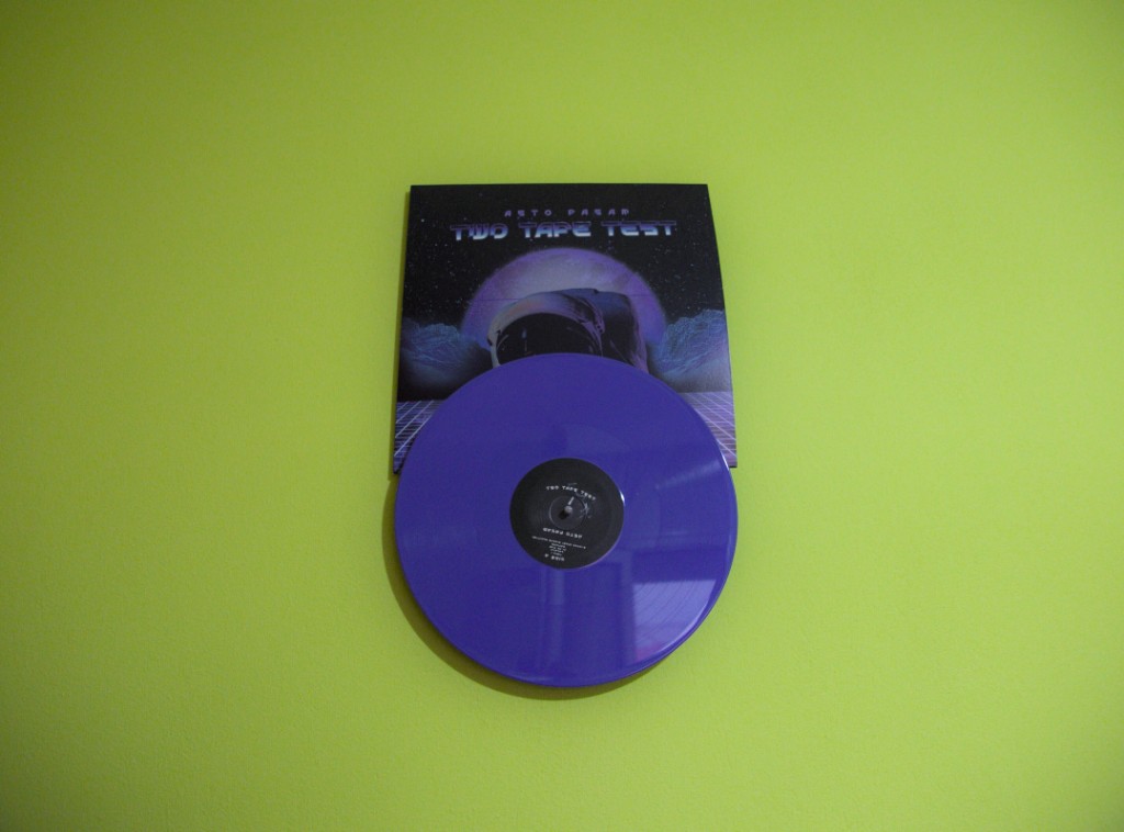 Purple vinyl record and space-themed Two Tape Test album cover by Reto Pagan on a lime-green wall with a minimalist vinyl wall mount display