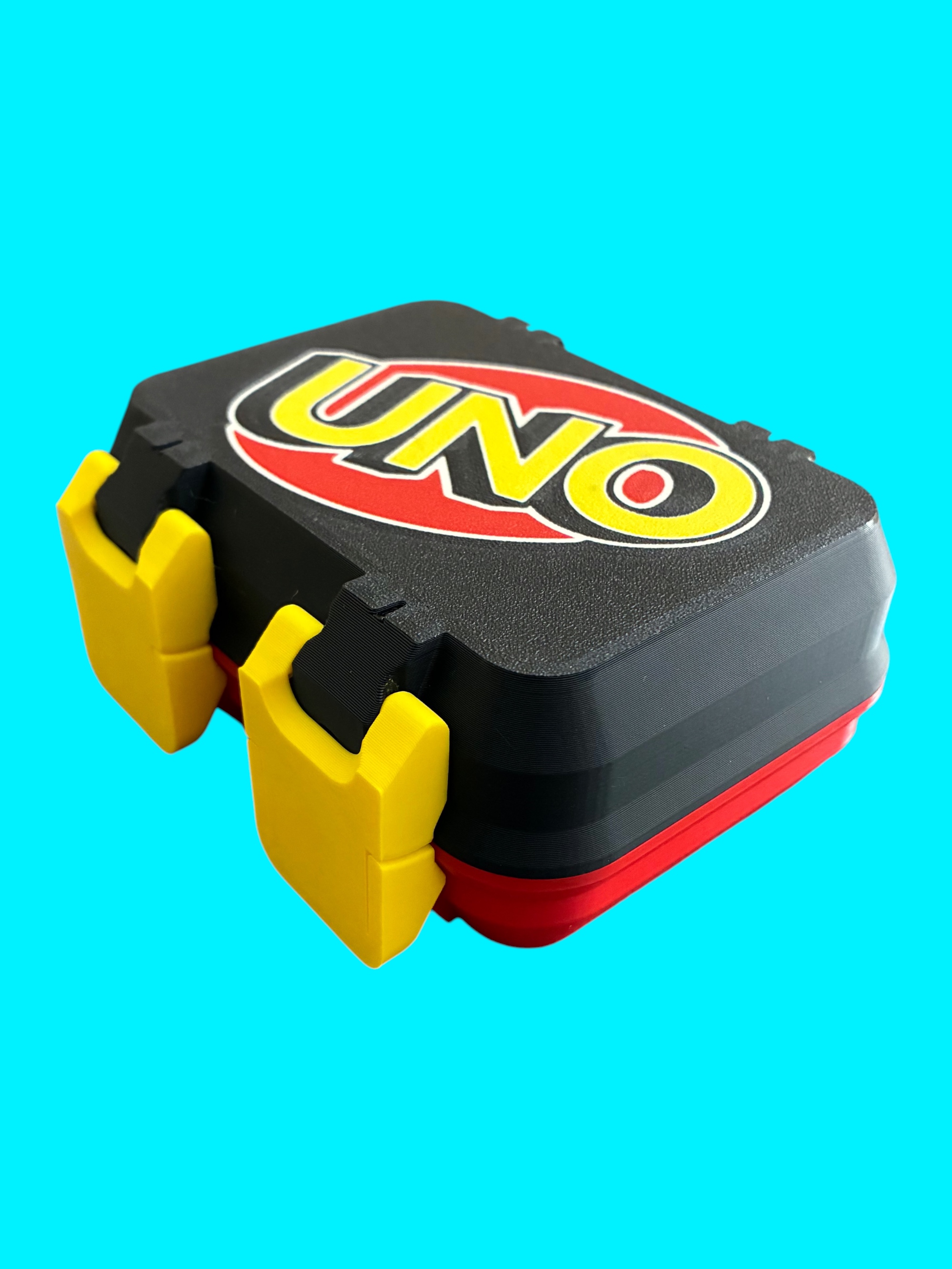 Black and red 3D-printed UNO card storage case with yellow latches and the UNO logo on top